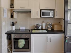 a kitchen with a stove and a microwave at Ramscliff Cottage in Cheddar