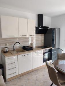 een keuken met witte kasten, een tafel en een wastafel bij Apartment Seman in Vela Luka