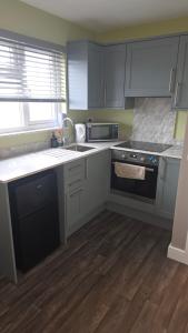 a kitchen with white cabinets and a black stove at Studio apartment in Fishponds in Bristol +8 photos