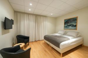 a bedroom with a bed and a chair at T10 Self check-in Hotel in Hafnarfjördur