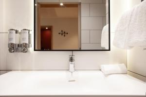 a bathroom with a sink with a mirror above it at Hampton By Hilton Stuttgart Airport in Filderstadt +179 photos