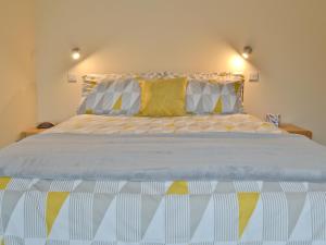 Un dormitorio con una cama grande con almohadas amarillas y blancas. en Mendip, en Cheddar