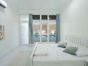 a white bedroom with a large bed and a large window at Al-Salam Villa-Family Pool & Private Garden in Misfāh +44 photos