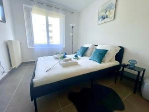 Un dormitorio con una cama con almohadas azules y una ventana. en L'Azur de Clamart, en Clamart 3 fotos más