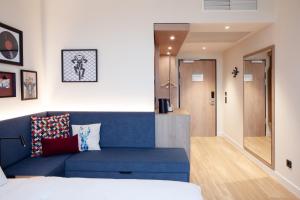 a living room with a blue couch in a room at Hampton By Hilton Stuttgart Airport in Filderstadt