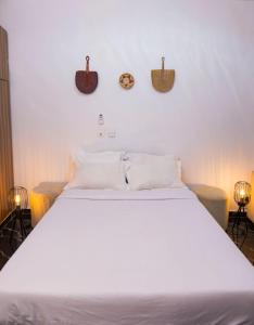 a bedroom with a large white bed with three clocks on the wall at Casa Hôtel Résidence in Abidjan