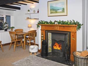 a living room with a fireplace and a dining room table at Osprey Cottage in Bassenthwaite