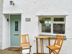 two chairs and a table in front of a house at Osprey Cottage in Bassenthwaite