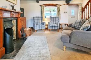 a living room with a couch and chairs and a fireplace at Osprey Cottage in Bassenthwaite