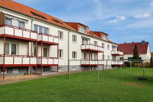an apartment building with red balconies and a green field at Moritz Apartments - Dosborn 7 in Dingelstädt