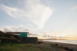 a house on the beach with the sun setting at Moinho da Areia - Boutique Hotel in Azores in Ribeira Grande