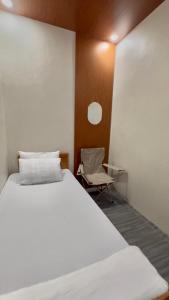Un dormitorio con una cama blanca y una silla. en Transient Room Near SM Lipa and LIMA PARK, en Inosloban