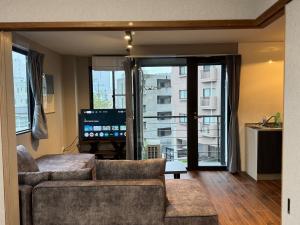a living room with a couch and a large window at UNITED GARDEN hotel 宇都宮駅前3階 in Utsunomiya