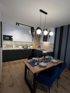 a kitchen with a wooden table and blue chairs at Apartament Ski &Sun in Świeradów-Zdrój