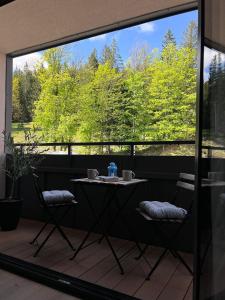 a table and chairs on a balcony with a large window at Apartament Ski &Sun in Świeradów-Zdrój