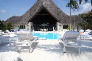 Un grupo de sillas blancas y una piscina. en Lilys Haven, en Malindi