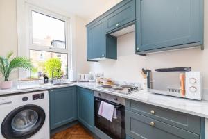 uma cozinha com armários azuis e uma máquina de lavar em Spacious Two Bed House in Headingley em Headingley