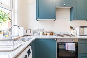 a kitchen with blue cabinets and a sink at Spacious Two Bed House in Headingley in Headingley