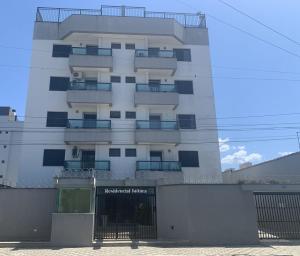 a tall white building with a fence in front of it at Refúgio em Ubatuba - Perto de tudo in Ubatuba