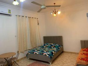 a bedroom with a bed and a table and a ceiling fan at Kourosh in Muscat