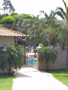 a house with palm trees in front of a fence at Rancho com acesso direto ao rio, área verde e lazer completo in Santa Fé do Sul