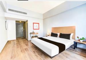 a bedroom with a large white bed and wooden floors at Hotel O Vemulawada Temple Formerly Kamakshi Bliss in Vemalwāda +17 photos