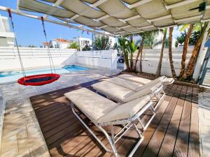 a porch with two chairs and a swing at Beach Villa With Private Pool And BBQ in Pervolia