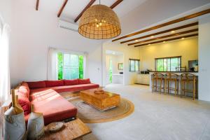a living room with a red couch and a table at Serene Jungle Escape with Private Pool by Sea N' Rent in Haad Chao Phao