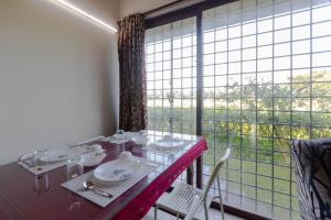 a dining room with a table and a large window at Villa Vedic Oasis by JadeCapsPool4 BHKAC in Sikarpur