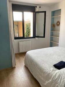 een slaapkamer met een wit bed en een raam bij Charming house - Grand Village Plage in Grand-Village-Plage +15 foto's