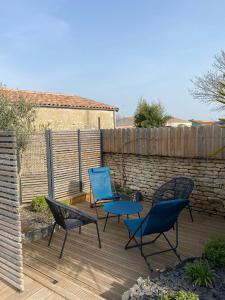 drie stoelen en een tafel op een houten terras bij Charming house - Grand Village Plage in Grand-Village-Plage