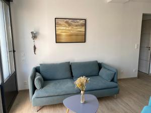 een woonkamer met een blauwe bank en een tafel bij Charming house - Grand Village Plage in Grand-Village-Plage