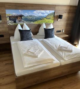 a large bed with white sheets and pillows at Platzhirsch Rooms - B&B - SELF CHECK-IN in Piesendorf