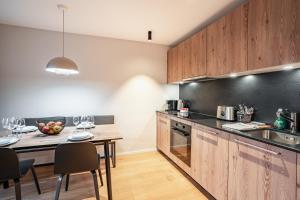 a kitchen with wooden cabinets and a table with chairs at SWISSPEAK Resorts by Pierre & Vacances Premium Thyon in Hérémence