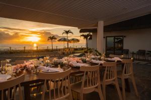 einen Tisch am Strand mit Sonnenuntergang im Hintergrund in der Unterkunft Balay Angkan Beachfront Villas Zambales in Cabangan