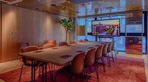 a long table and chairs in a room with a projection screen at Marski by Scandic in Helsinki