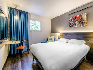 een hotelkamer met een groot bed en een tv bij Greet Hotel Bordeaux Floirac Arena in Floirac