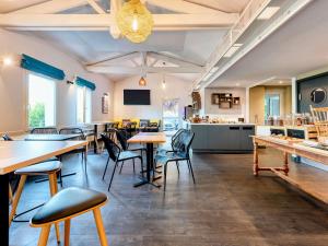 een restaurant met tafels en stoelen en een keuken bij Greet Hotel Bordeaux Floirac Arena in Floirac