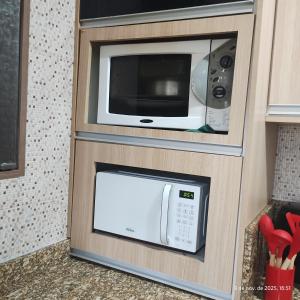 a microwave in a wooden cabinet with a microwave oven at Apartamento Embaúbas in São José