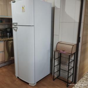a white refrigerator in a kitchen next to a shelf at Apartamento Embaúbas in São José