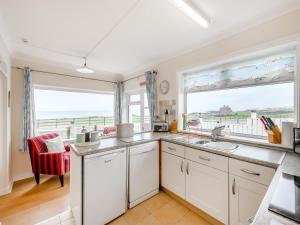 a kitchen with white cabinets and a large window at Toll Bar Cottage in Whitby