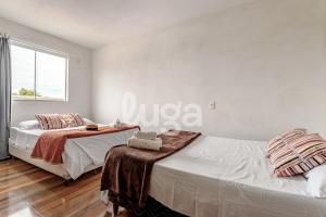 two beds in a white room with a window at LUGA: Peaceful Retreat | Lagoon & Imbituba in Imbituba