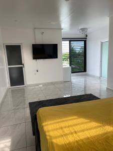 1 dormitorio con cama amarilla y TV de pantalla plana en Cozy home North, en Paramaribo