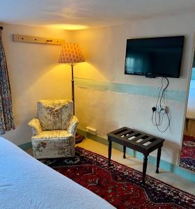 a hotel room with a chair and a tv at Lamb Inn in Wartling