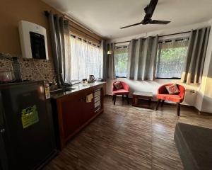 a kitchen with a refrigerator and two chairs in it at The Burrow in South Goa. in Dabolim +16 photos