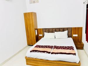 a bedroom with a large bed with a wooden headboard at Hotel Shri Ram Palace in Jhālāwār