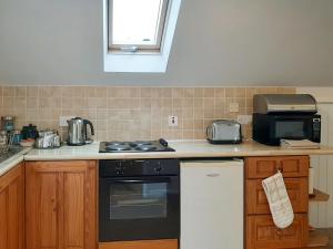 eine Küche mit Herd und Mikrowelle in der Unterkunft Forge Cottage - 28221 in Shaldon