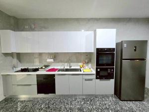 東港鎮にある東港包棟 悠舍民宿の白いキャビネットと黒い冷蔵庫のあるキッチン