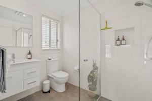 a white bathroom with a toilet and a glass shower at Casa de Soleil New Modern Home Central Location in Worragee +21 photos