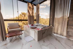 a bathroom with a sink and a chair and large windows at Cabana Morada nas Nuvens in Pinto Bandeira